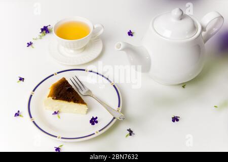 Délicieux cheesecake basque brûlé avec un chapeau de thé et une théière au moment de la pause-café. Banque D'Images