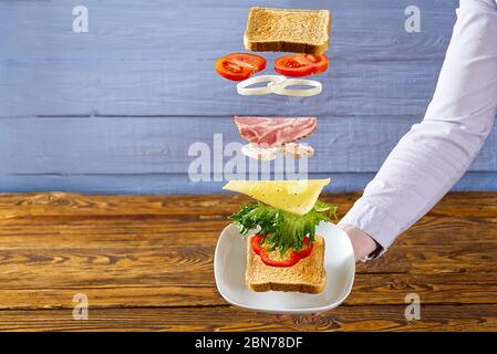 sandwich volant. Couches volantes de sandwich. Patty, jambon, fromage et légumes bien rôtis entre deux moitiés d'un. Concept de la cuisine américaine du petit déjeuner. Banque D'Images