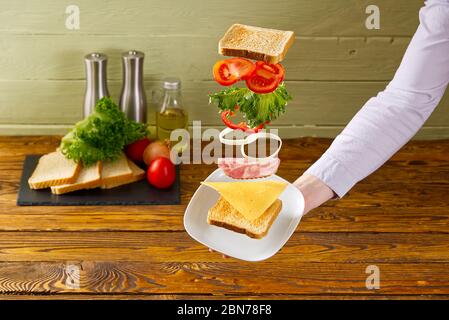 sandwich volant. Couches volantes de sandwich. Patty, jambon, fromage et légumes bien rôtis entre deux moitiés d'un. Concept de la cuisine américaine du petit déjeuner. Banque D'Images