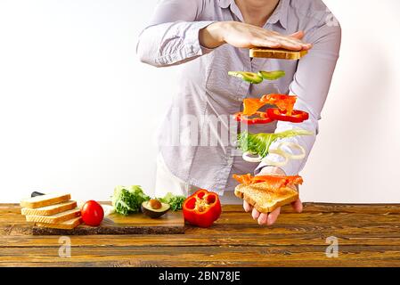 sandwich volant. Couches volantes de sandwich. Patty, jambon, fromage et légumes bien rôtis entre deux moitiés d'un. Concept de la cuisine américaine du petit déjeuner. Banque D'Images