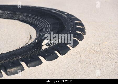 Grand pneu en caoutchouc noir laissé sur une plage de sable, concept de pollution de l'environnement Banque D'Images