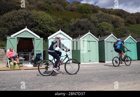 Les cyclistes qui ont passé des cabanes de plage sur la plage de Bournemouth à Dorset le premier jour de détente pour quelques restrictions de blocage du coronavirus en Angleterre. Banque D'Images