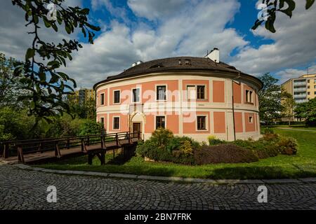 Prague / République tchèque - Mai 12 2020: Vue sur la fotress de Chodov avec façade jaune et rouge debout dans un parc avec pelouse verte et arbres. Soleil le jour du printemps. Banque D'Images