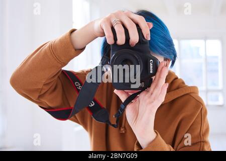 hipster fille tenant canon 6d avec 50 mm f/1.8 et prenant des photos. gros plan de la main de la jeune femme avec un appareil photo professionnel en studio. photographie du monde Banque D'Images