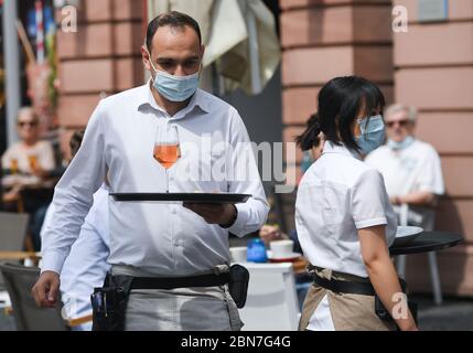 Mayence, Allemagne. 13 mai 2020. Aris Astanoglou (l) et son collègue servent 'Wilma Wunder' sur la Domplatz Mainzer avec des bouteurs dans la zone extérieure du restaurant. Les restaurants et les pubs de Rhénanie-Palatinat ont été autorisés à rouvrir en vertu de réglementations strictes depuis le 13 mai 2020. Crédit : Arne Dedert/dpa/Alay Live News Banque D'Images