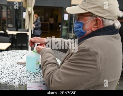 Mayence, Allemagne. 13 mai 2020. Klaus Schmidt désinfecte ses mains dans la zone extérieure du restaurant « Wilma Wunder » sur la place de la cathédrale de Mayence. Les restaurants et les pubs de Rhénanie-Palatinat ont été autorisés à rouvrir en vertu de réglementations strictes depuis le 13 mai 2020. Crédit : Arne Dedert/dpa/Alay Live News Banque D'Images