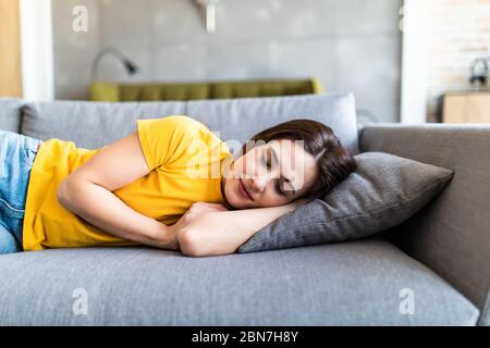 Portrait de jeune fille brune mignonne dormant sur le canapé dans le salon léger. Banque D'Images