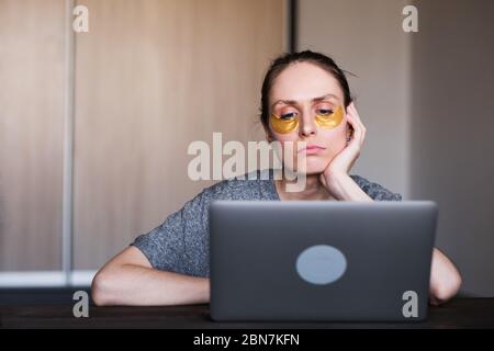 Elle s'assied jeune femme assis à la table de la maison, elle utilise des plaques d'hydrogel. Banque D'Images