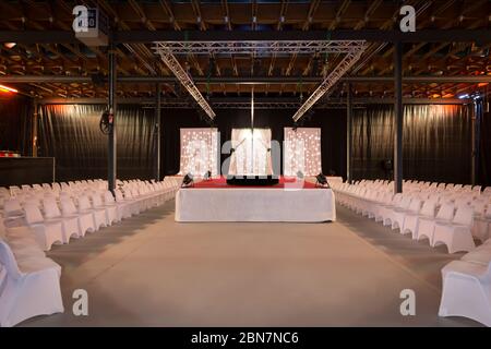 Scène de tapis rouge avec poteau de danse, rangées de chaises blanches et treillis d'éclairage de scène métallique Banque D'Images