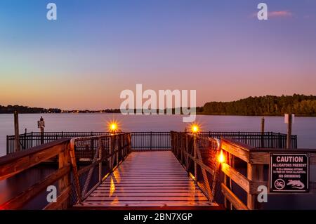 Coucher de soleil depuis un quai surplombant un lac avec des Gators à Orlando, Floride Banque D'Images