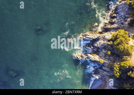 vue aérienne de l'océan turquoise avec des vagues de mer qui s'écrasant sur la côte de l'île rocheuse avec des jets et de la mousse, concept de style de vie d'aventure et de ho d'été Banque D'Images