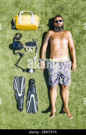 flat lay d'un photographe sous-marin dans un maillot de bain avec son appareil photo et son équipement de plongée sur un fond d'herbe, vue de dessus Banque D'Images