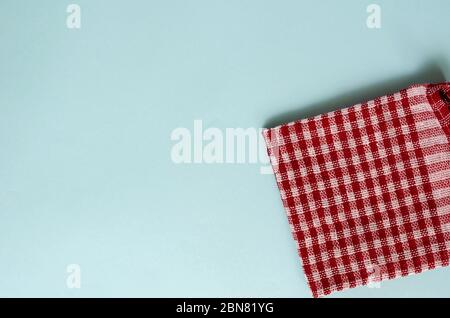 Fond turquoise clair avec une serviette de cuisine rouge. Serviette ou serviette pliée en lin fragment à carreaux. Arrière-plan minimaliste pour le multitâche. Vue de abo Banque D'Images