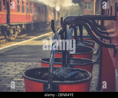 Vue rapprochée rétro des seaux à feu d'époque suspendus sur la plate-forme de la gare du patrimoine, Severn Valley Railway UK, train à vapeur d'époque part. Banque D'Images