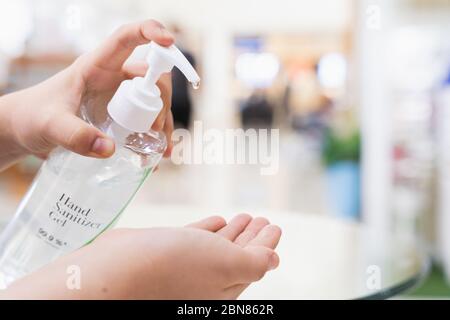 les femmes en gros plan utilisent du gel d'alcool pour se laver les mains afin de protéger la maladie du coronavirus dans le magasin. Concept pendant la maladie du coronavirus COVID-19. Banque D'Images