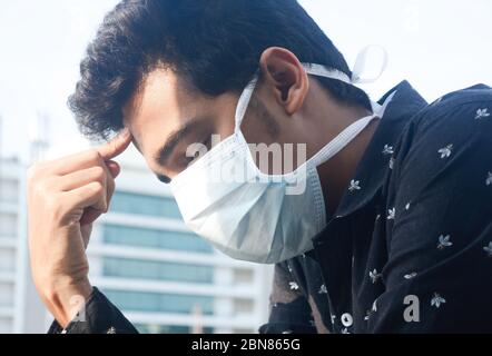 Jeune homme portant un masque de visage pensant comment résoudre le puzzle de virus corona. Banque D'Images