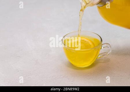 Immunité dopez le thé curcuma versé dans une tasse de verre sur fond clair neutre avec espace pour le texte Banque D'Images