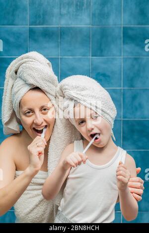 Une femme et un garçon avec des serviettes sur la tête se brossant les dents. Banque D'Images