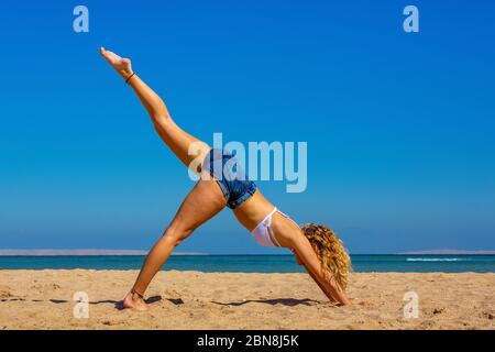 Jeune femme blonde en posture de yoga droite sur la plage égyptienne Banque D'Images