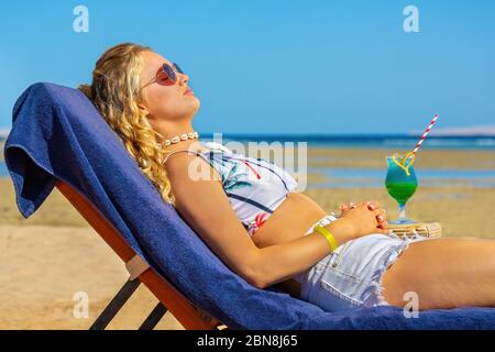 Jeune femme caucasienne bronze sur un lit de plage près de la mer égyptienne Banque D'Images