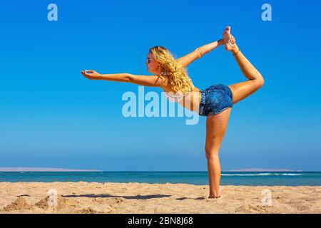 Jeune femme blonde en yoga pose sur la plage égyptienne Banque D'Images