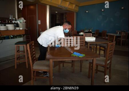 Malaga, Espagne. 13 mai 2020. Un employé nettoie une table à l'intérieur de la barre de coquillages « Godoy » avant de la rouvrir pendant le confinement partiel après le début de la phase 1 dans certaines villes.l'Espagne passe par un plan de réduction vers une « nouvelle normalité » en assouplissant les mesures résultant de l'épidémie de COVID-19, des villes comme Madrid, Barcelone, Malaga ou Grenade continuent dans la phase 0 en raison des avis épidémiologiques des autorités sanitaires. Crédit : SOPA Images Limited/Alamy Live News Banque D'Images