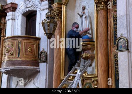 Lisbonne, Portugal. 12 mai 2020. Un auxiliaire de l'église catholique de Penha de França aide à abaisser la sculpture de la Vierge de Fatima de son piédestal pour être préparé et porté en procession à travers les rues pendant la célébration.traditionnellement, c'est une procession de dévotés qui remplissent les rues de Lisbonne, Aujourd'hui, il est réduit à regarder des fenêtres de leurs maisons le passage de l'image représentative à travers un véhicule pendant la célébration de la Fête de la Vierge de Fatima. Crédit : SOPA Images Limited/Alamy Live News Banque D'Images