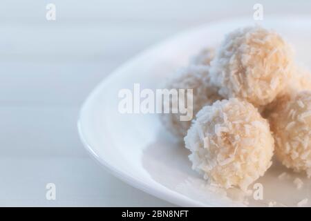 Boules de bonbons à la noix de coco dans un plat recouvert de chocolat et de noix de coco déchiquetées sur fond rustique en bois. Bonbons maison faits maison avec des flocons de noix de coco. Définir c Banque D'Images