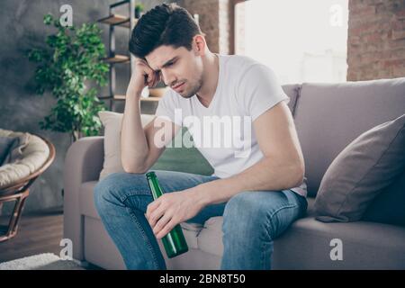 Portrait de son beau attrayant déçu misérable déprimé mec assis sur le divan boire de la bière se sentant mal à l'industrie moderne loft brique Banque D'Images