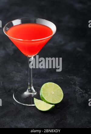 Cocktail cosmopolite en verre cristal classique avec des limbes sur fond de table noire. Banque D'Images