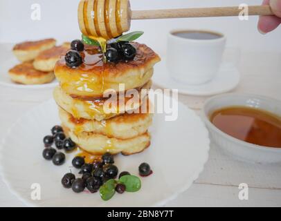 Beignets. Crêpes traditionnelles dans une pile sur une assiette blanche. Baies et miel. Café ou thé Banque D'Images