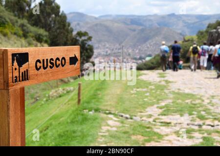 Un signe avec une grande flèche pointant vers la gauche. En arrière-plan, il est possible de voir un village. Photo prise à Cusco, Pérou Banque D'Images