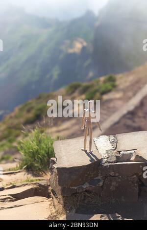 Un homme en bois se dresse sur une falaise d'une montagne au bord du précipice et regarde la distance au soleil Banque D'Images