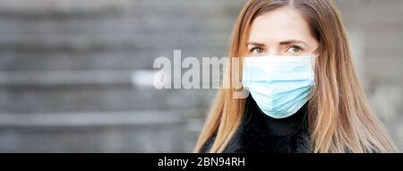 Jeune femme portant un virus bleu jetable visage bouche masque de nez, portrait de gros plan, bannière avec espace pour le texte côté gauche. Épidémie de coronavirus covid-19 Banque D'Images