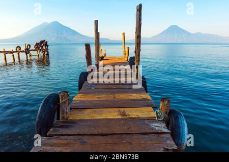 Le lac Atitlan près de Panajachel avec des pêcheurs sur un quai et deux volcans en arrière-plan, le Guatemala. Banque D'Images