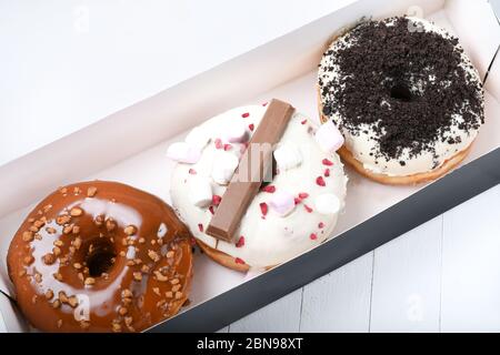 Trois fondus émaillés de chocolat noir et blanc, marshmallows, biscuit crumbles, beignets enrobés de sucre caramel sur bois blanc Banque D'Images