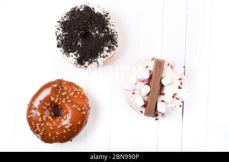 Trois fondus émaillés de chocolat noir et blanc, marshmallows, biscuit crumbles, beignets enrobés de sucre caramel sur bois blanc Banque D'Images