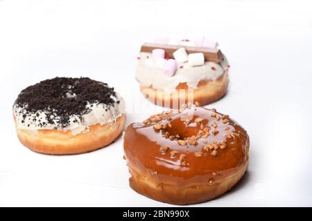 Trois fondus émaillés de chocolat noir et blanc, marshmallows, biscuit crumbles, beignets enrobés de sucre caramel sur bois blanc Banque D'Images