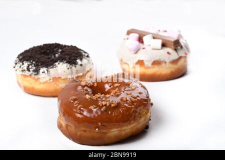 Trois fondus émaillés de chocolat noir et blanc, marshmallows, biscuit crumbles, beignets enrobés de sucre caramel sur bois blanc Banque D'Images