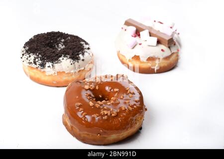 Trois fondus émaillés de chocolat noir et blanc, marshmallows, biscuit crumbles, beignets enrobés de sucre caramel sur bois blanc Banque D'Images