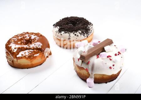 Trois fondus émaillés de chocolat noir et blanc, marshmallows, biscuit crumbles, beignets enrobés de sucre caramel sur bois blanc Banque D'Images