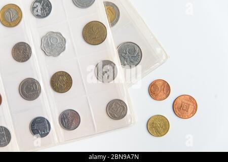 Mise à plat des feuilles et pièces de l'album numismatique. Collection de pièces différentes sur le blanc avec espace de copie Banque D'Images