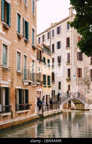 Venise, Italie - 04 octobre 2019 : les touristes se promentent sur un pont arable au-dessus d'un petit canal vénitien, sur fond d'immeubles d'appartements sur le Banque D'Images
