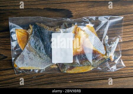 Dorade séchée en forme de papillon dans un emballage transparent avec un apéritif de marque blanche à la bière sur fond de bois. Snack Fish à la bière. Gros plan Banque D'Images