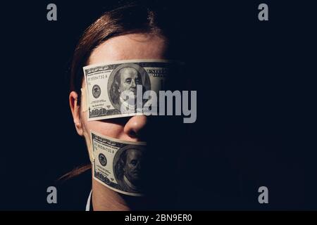 Femme avec des billets de dollars couvrant ses yeux et la bouche, concept d'économie, richesse, corruption Banque D'Images