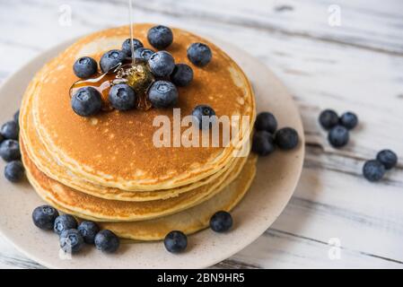 Gros plan d'une pile de crêpes moelleuses avec du sirop d'érable versé dessus. Banque D'Images
