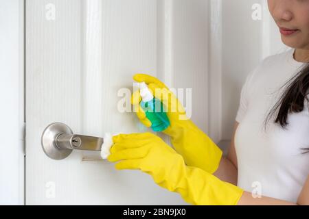 Femme asiatique désinfectant les boutons de porte en vaporisant un désinfectant bleu à partir d'une bouteille. Prévenir le virus et les bactérias, prévenir le covid19, coronavirus, ALC Banque D'Images