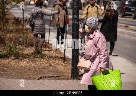 Montréal, CA - 13 mai 2020 : femme avec masque facial pour la protection contre la COVID-19 en descendant la rue Laurier Banque D'Images