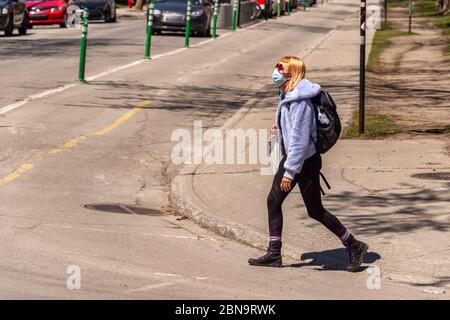 Montréal, CA - 13 mai 2020 : femme avec masque facial pour la protection contre la COVID-19 en descendant la rue Laurier Banque D'Images