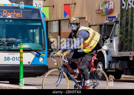 Montréal, CA - 13 mai 2020 : un homme avec un masque facial à vélo pendant la pandémie du coronavirus COVID-19. Banque D'Images